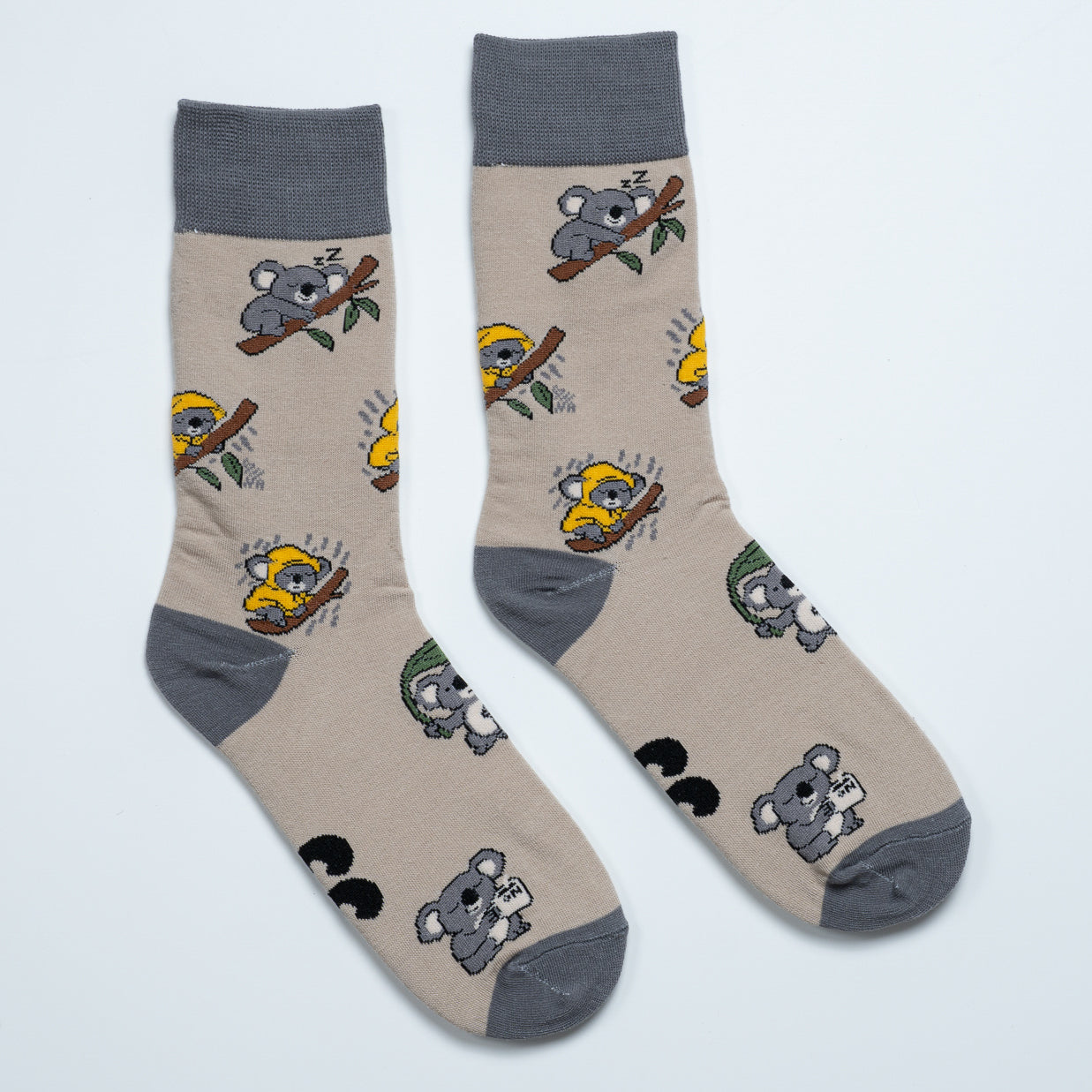 Pair of beige koala socks laid side by side with sleeping and raincoat koala illustrations