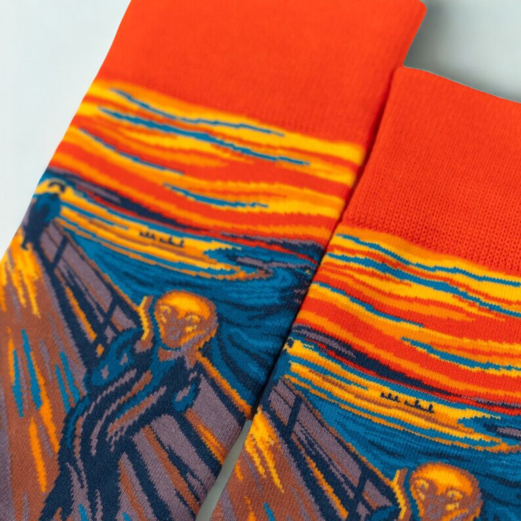 Close-up of The Scream knitted artwork and bright orange cuffs on two crew socks
