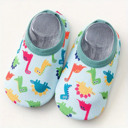 Pair of baby shoes with colorful dinosaur pattern on a light blue background