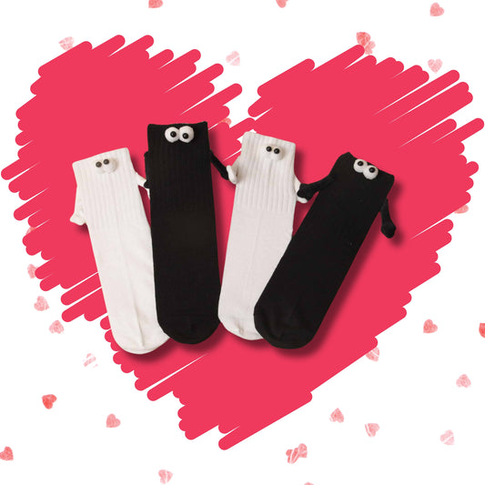 Black and white Soulmates socks with character eyes and holding hands on a pink heart background