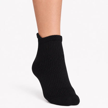 Black ankle compression sock worn from the front to show its supportive ribbed fit