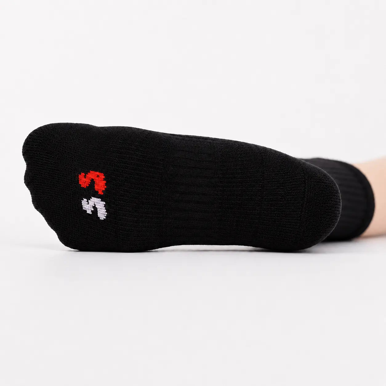 Sole of a black ankle compression sock showing the cushioned footbed and coloured size markers