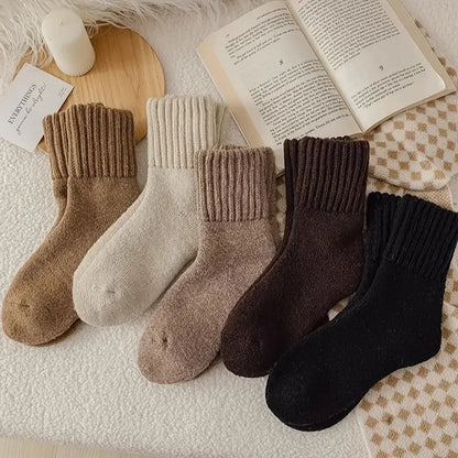 Five pairs of cashmere wool socks lined up in neutral black, brown, beige and cream colours