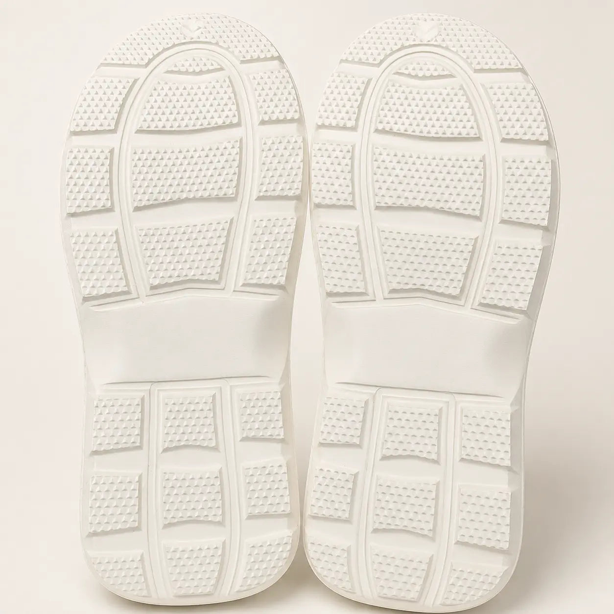 Close-up of white shoes with textured sole on a light background