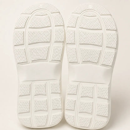 Close-up of white shoes with textured sole on a light background