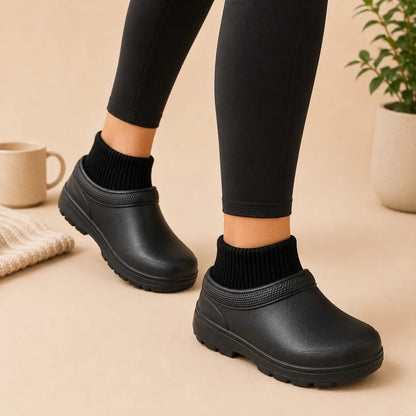 Black slip-on shoes worn with black leggings on a beige background