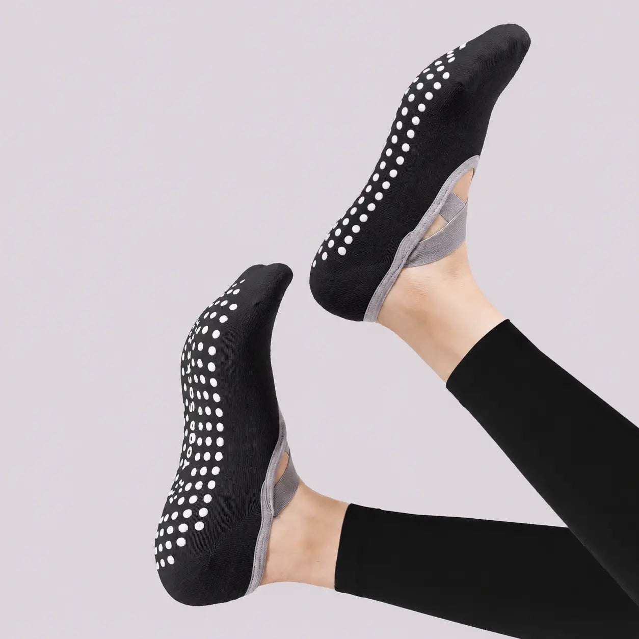 Black Pilates socks shown from the soles to highlight the white non-slip grip dots