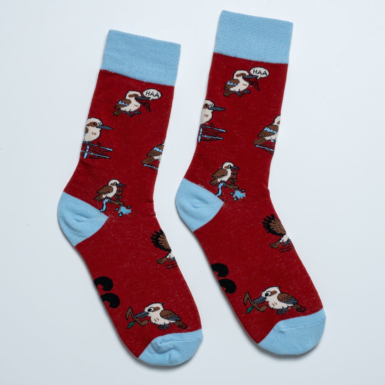 Pair of red kookaburra socks laid side by side with playful laughing bird illustrations