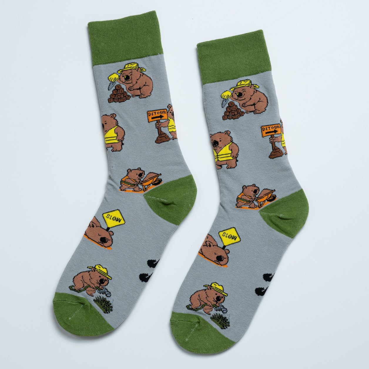 Pair of grey Wombat socks laid side by side with playful roadworks and construction illustrations