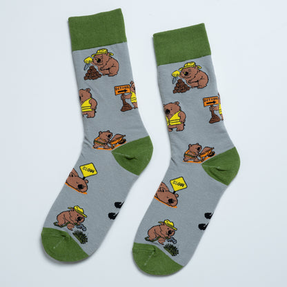 Pair of grey Wombat socks laid side by side with playful roadworks and construction illustrations