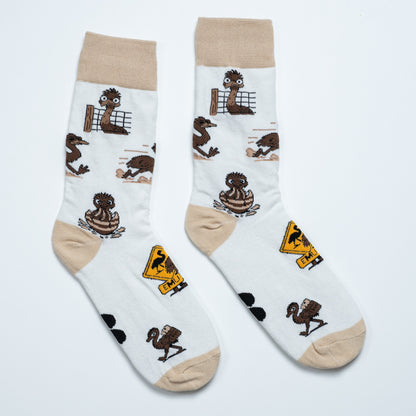 Pair of white emu socks laid side by side with playful emu scenes and an Australian road sign