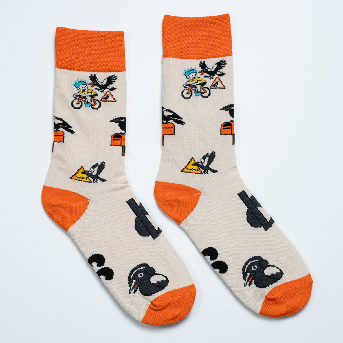 Pair of cream magpie socks laid side by side with swooping bird and cyclist illustrations