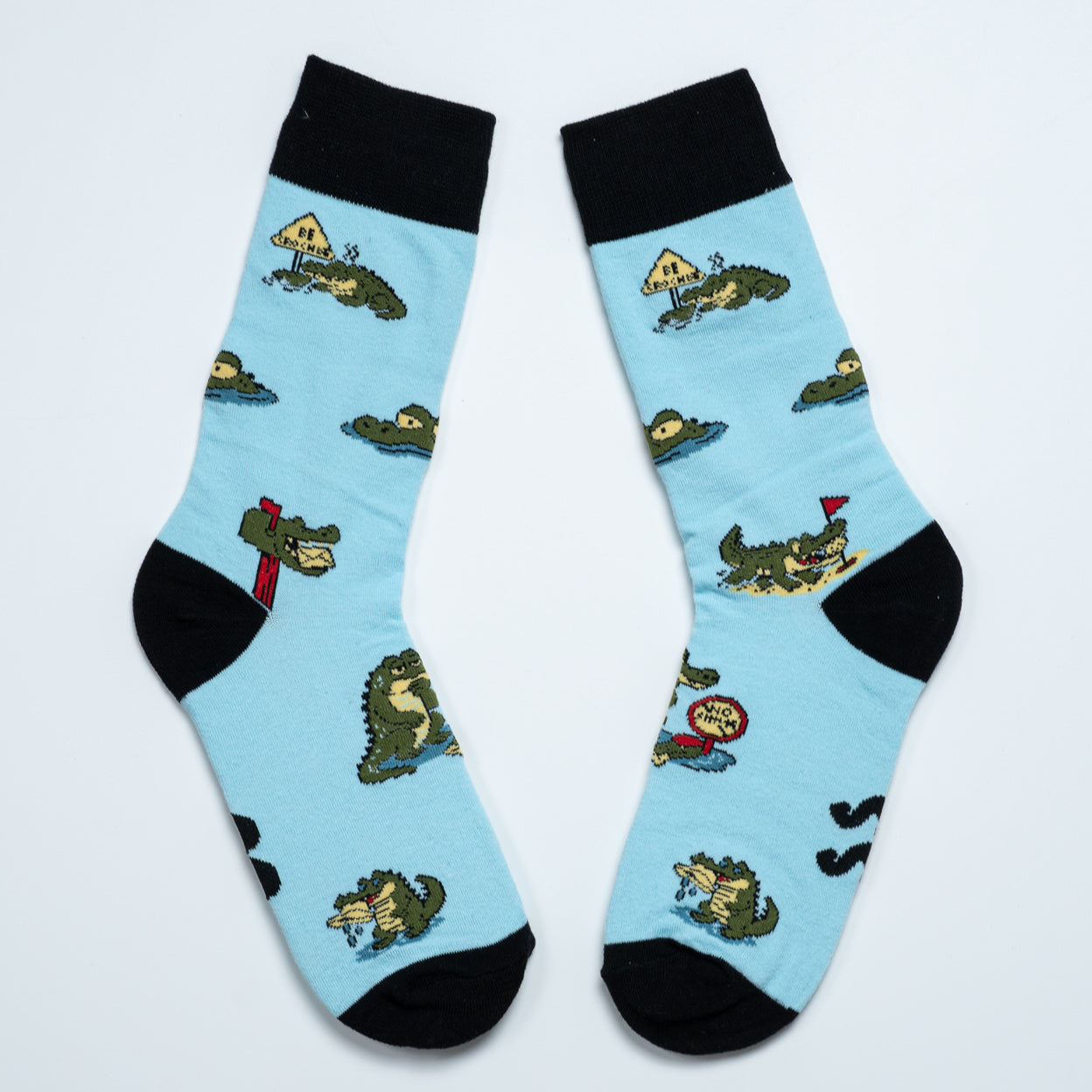 Pair of light blue crocodile socks laid diagonally with black cuffs, heels and toes