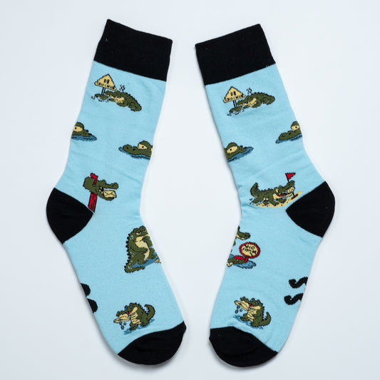 Pair of light blue crocodile socks laid diagonally with black cuffs, heels and toes