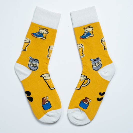 Yellow beer-themed crew socks laid diagonally with white cuffs, heels and toes