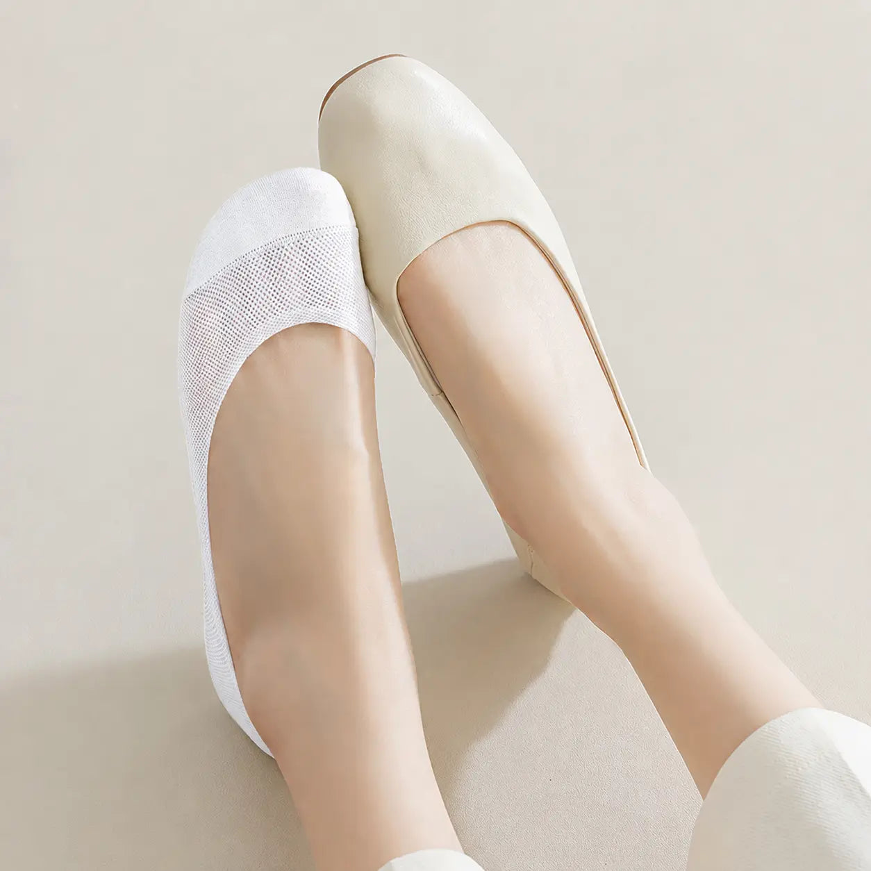White BareLite footie sock worn with a low-cut cream flat shoe