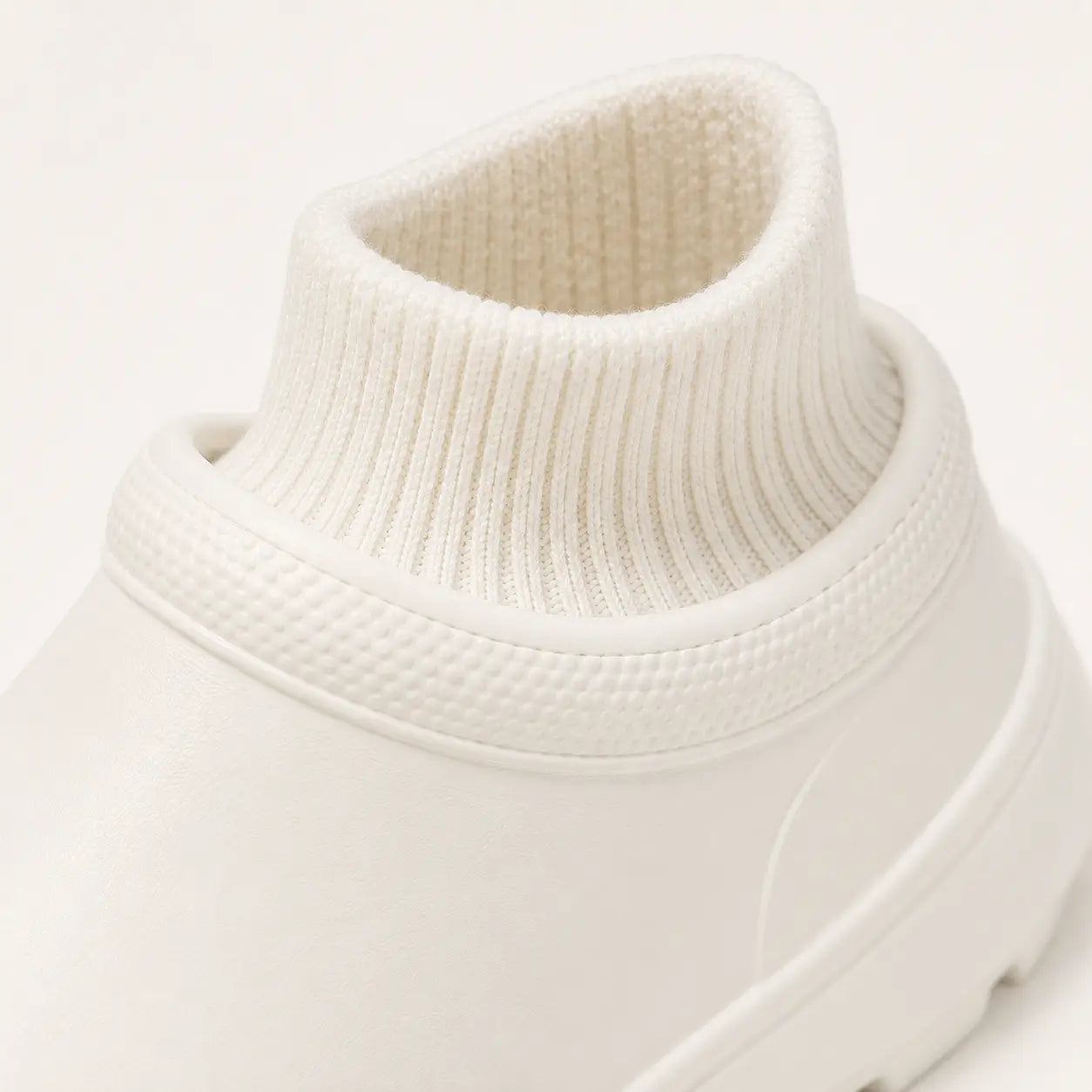 Close-up of a white turtleneck sweater on a light gray background