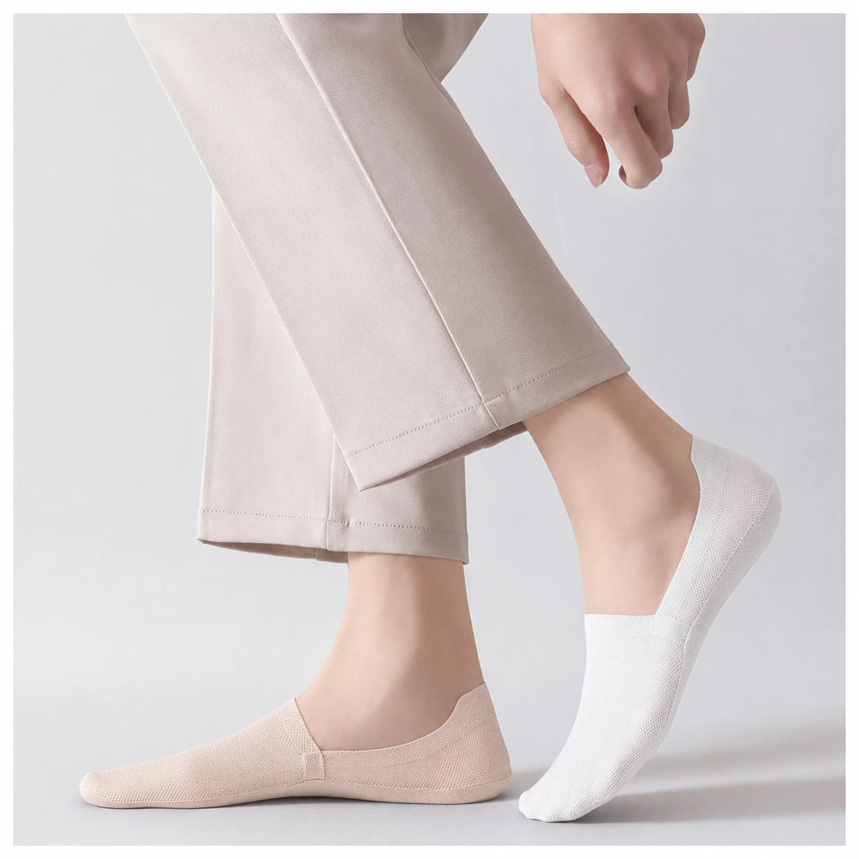 White and nude invisible socks worn side by side with neutral trousers