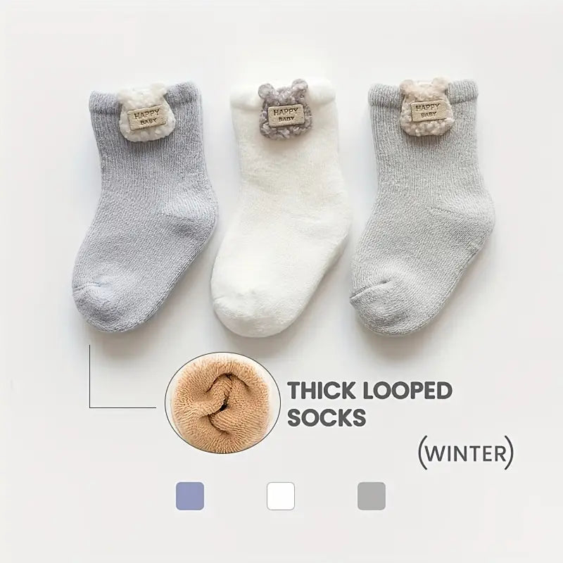 Three thick baby socks in blue, cream and grey with soft looped winter lining