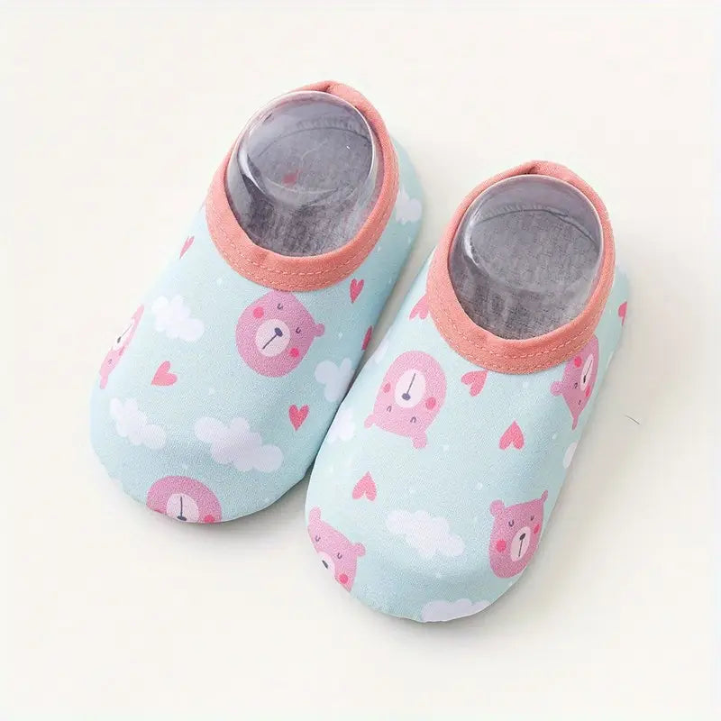 Pair of baby shoes with pink bear pattern on a light blue background