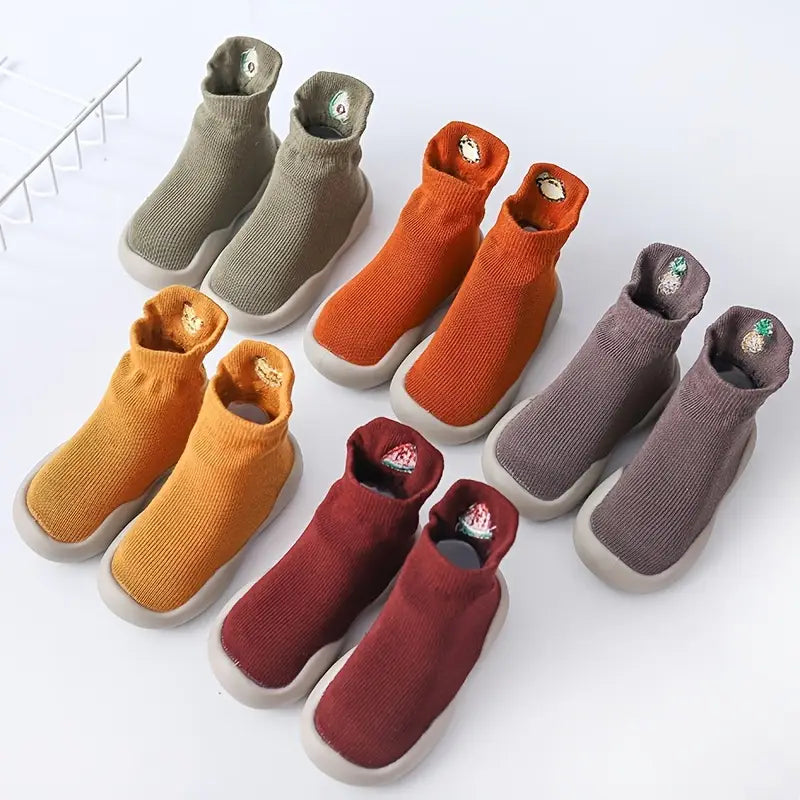 Five pairs of colourful Mini Walker sock shoes arranged on a white studio background