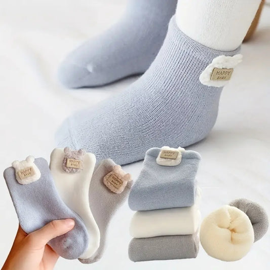 Baby wearing light blue Cloudy Cuddles socks with the blue, cream and grey three-pack displayed below