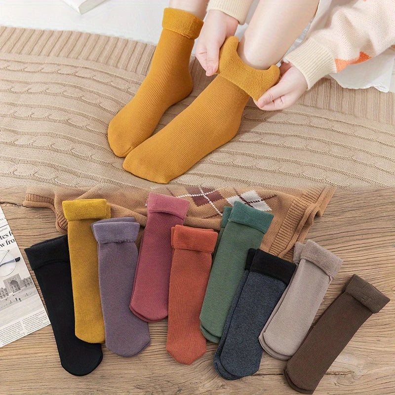 Woman wearing mustard fleece-lined indoor socks with assorted warm sock colours displayed below