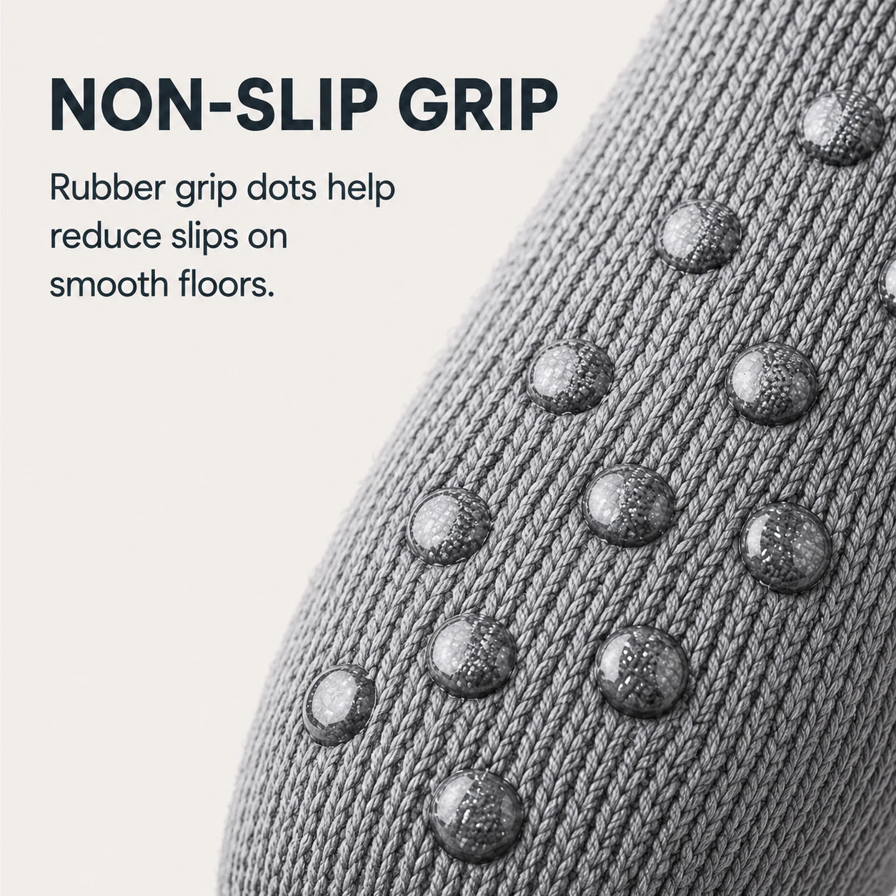 Close-up of a gray knit sock with raised rubber grip dots on a light beige background, with text reading 'NON-SLIP GRIP' and a descriptive feature callout.