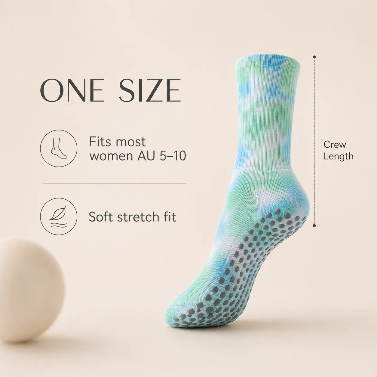 A single crew-length grip sock in a light blue and mint green tie-dye pattern with gray non-slip dots on the sole, shown next to text reading 'ONE SIZE' with fit and crew length information on a warm beige background.