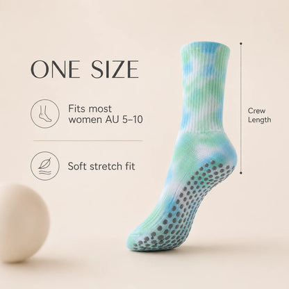 A single crew-length grip sock in a light blue and mint green tie-dye pattern with gray non-slip dots on the sole, shown next to text reading 'ONE SIZE' with fit and crew length information on a warm beige background.