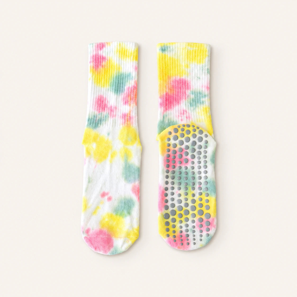 A pair of white crew socks with a pastel tie-dye pattern in pink, yellow, and mint green, featuring a textured grip sole with circular suction cups.