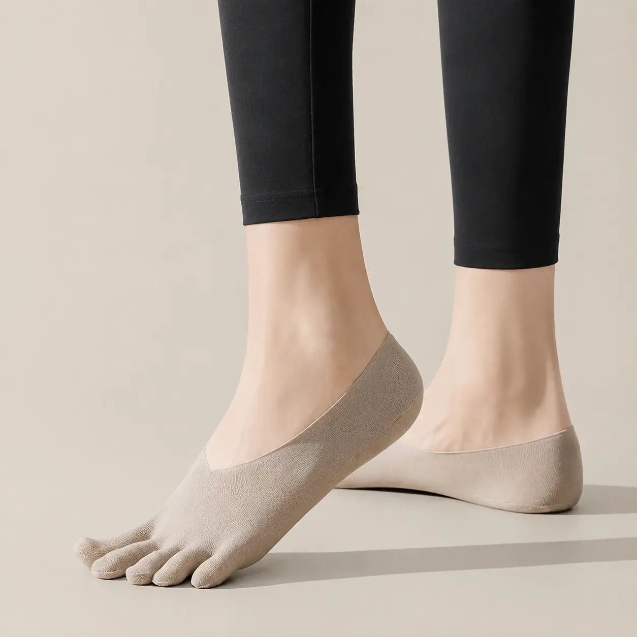 Sand beige BareToe five-toe invisible socks worn with black leggings in a studio