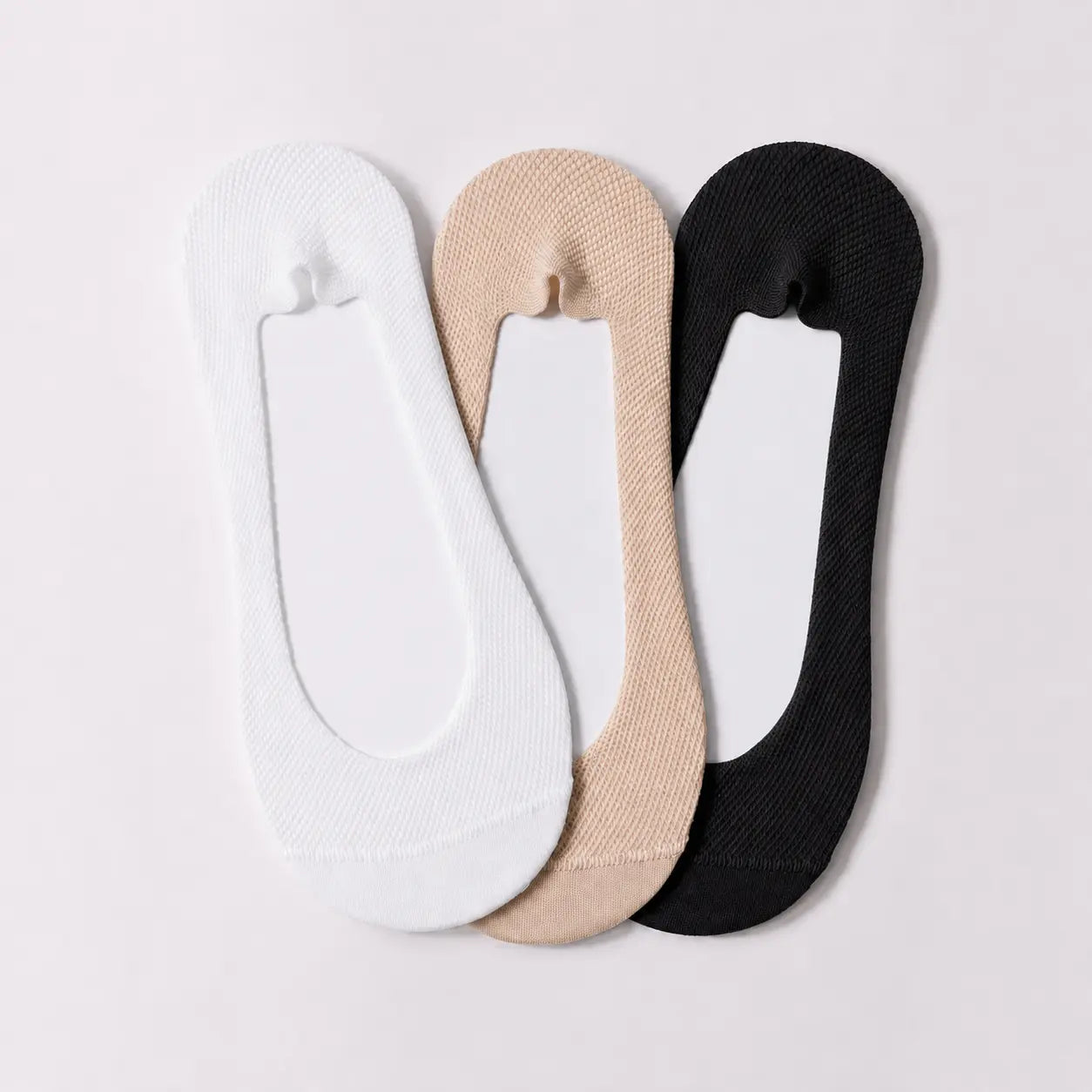 White, nude and black BareLite ultra low-cut footie socks laid flat together