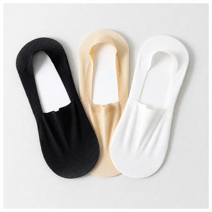 Black, nude and white invisible socks laid flat together on a light background